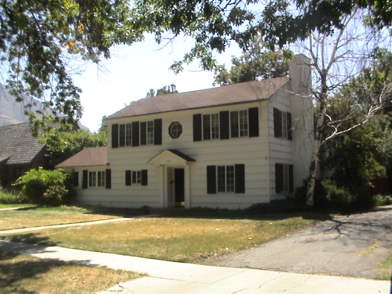 Two-story home before renovation, white siding and black shutters